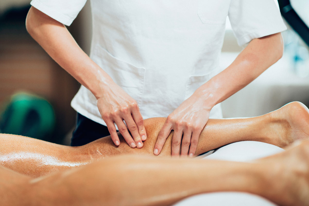 Sports massage therapist working on a client's leg at a Hermosa Beach massage studio